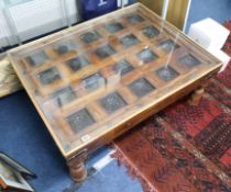 A carved wood Indian panelled coffee table with glass top, 78cm x 100cm x 40cm.