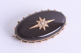 A large cabochon oval Onyx set with gold and seed pearl star, fitted with glass inset, stamped 15ct,