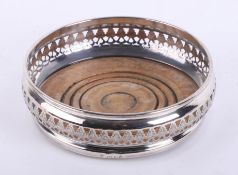 A single silver wine coaster with pierced filigree border, wood base and green baize bottom,