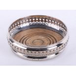 A single silver wine coaster with pierced filigree border, wood base and green baize bottom,