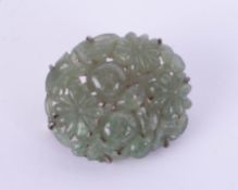 A jade brooch, carved with various flowers on a white metal clasp, approximately 33mm x 27mm.