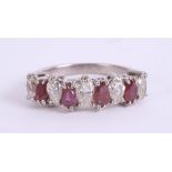 An 18ct white gold ruby and diamond ring, the nine stones of pear shape, size M.