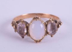 An antique three stone ring, set with an opal in unmarked yellow gold, size K/L.