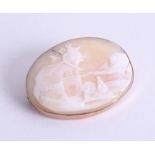 A rose gold oval cameo brooch depicting village scene, approx. 11.97g.