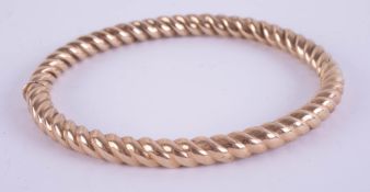A 9ct yellow gold and twist hinge bangle, approximately 14.2g.