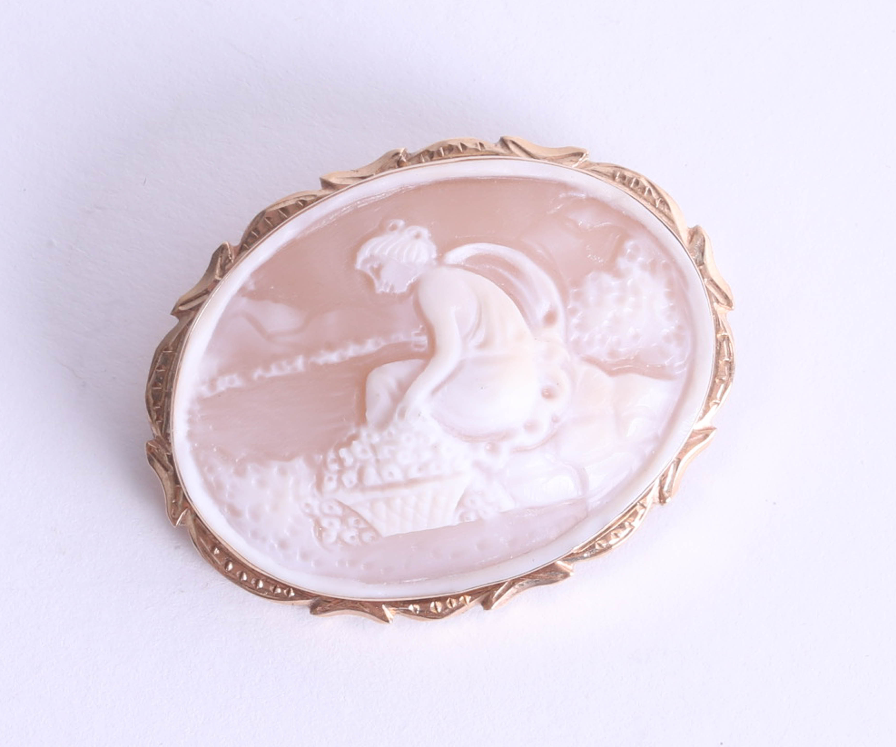 A 9ct gold oval cameo brooch depicting a seated lady with fruit basket, fancy hand engraved