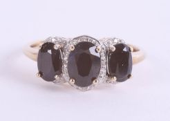 A three stone sapphire and diamond dress ring, set in yellow gold, size P.