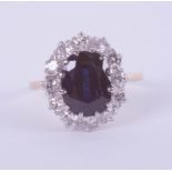 An 18ct white and yellow gold oval sapphire and diamond cluster ring, size K.