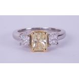 A fine 18ct diamond three stone ring, the centre stone yellow colour, two outer stones princess cut,