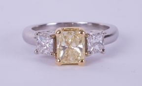 A fine 18ct diamond three stone ring, the centre stone yellow colour, two outer stones princess cut,