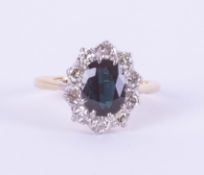 An 18ct white and yellow gold oval sapphire and diamond cluster ring, size O.