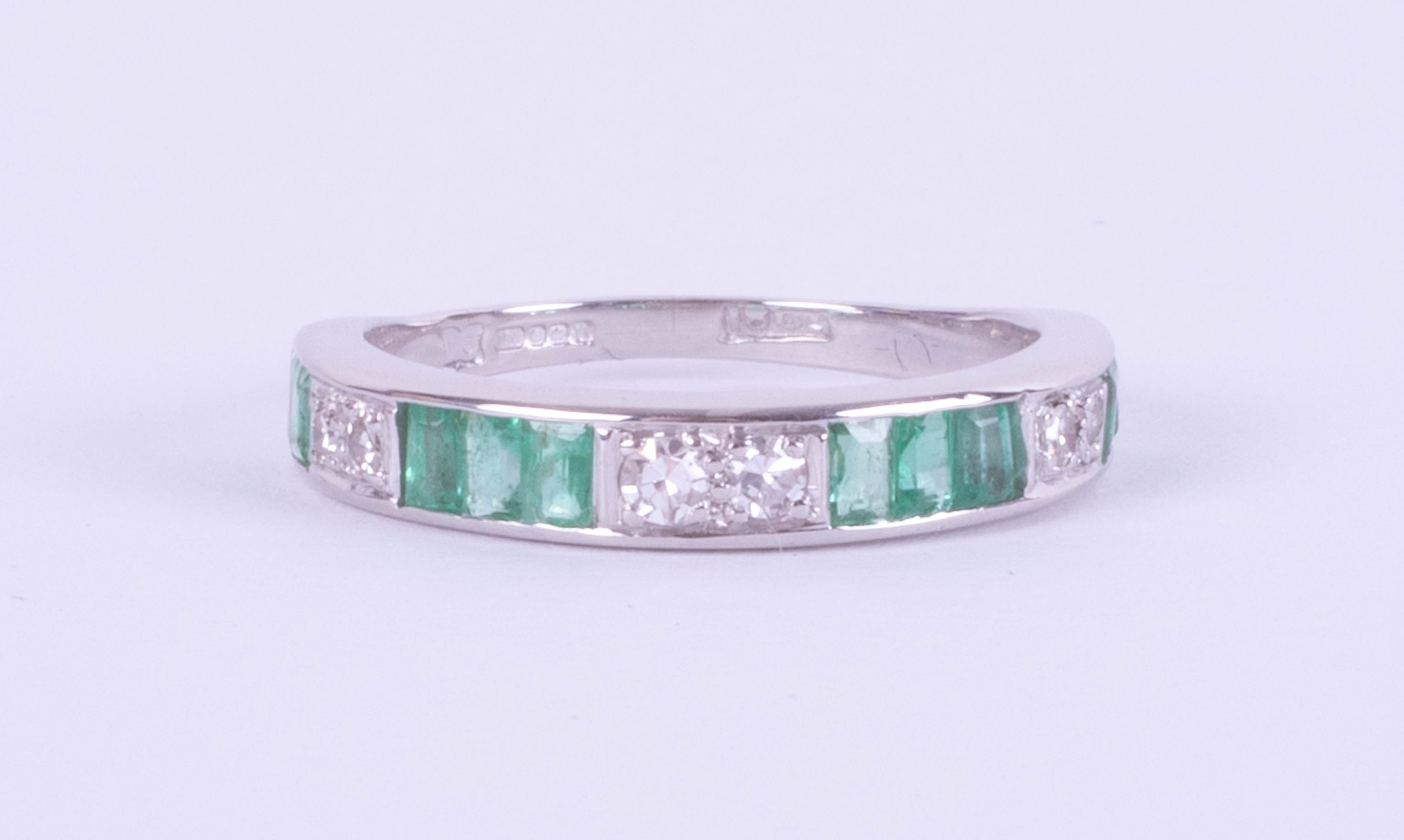 An 18ct white gold emerald and diamond half eternity ring, size M.