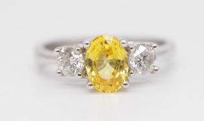 An 18ct yellow sapphire and diamond set three stone ring, size L.