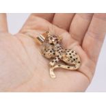 A diamond and sapphire set leopard pendant with ruby eyes, width approximately 35mm.