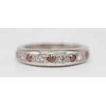 A heavy gauge platinum band ring set with red coloured and white diamonds, size U.
