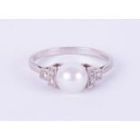 A platinum ring set with a single pearl and diamonds, size O.