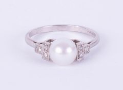 A platinum ring set with a single pearl and diamonds, size O.