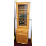 Ercol, a light wood glazed side cabinet bookcase, width 46cm, height 162cm.