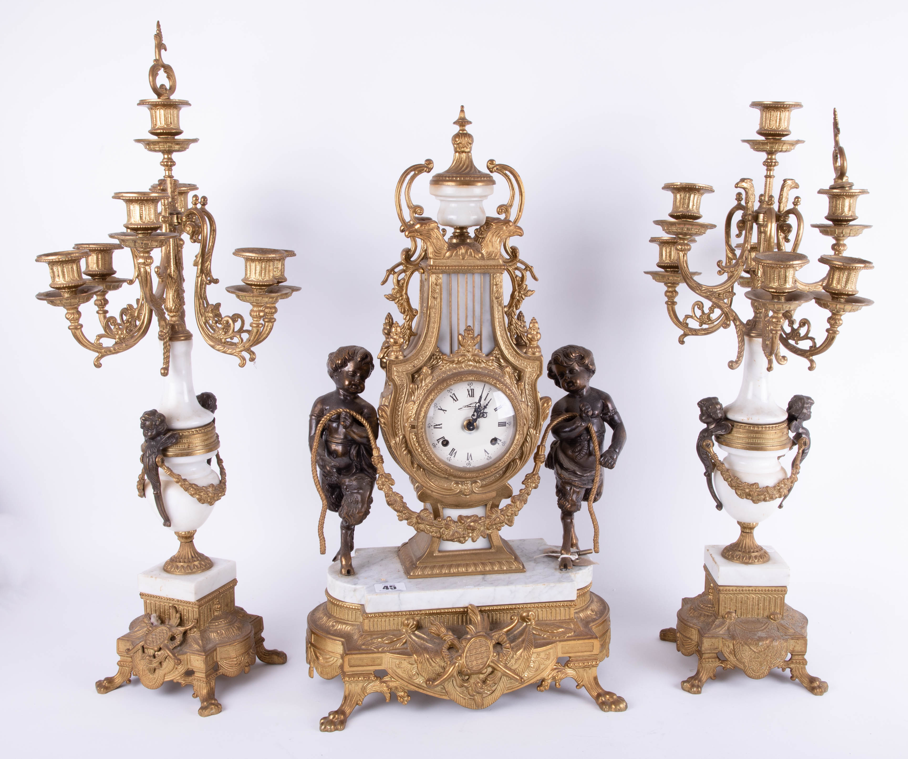 A large continental gilt and marble style three piece clock garniture set decorated with cherubs,