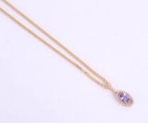 An 18ct tanzanite and diamond cluster pendant set in yellow gold on fine 18ct chain, total weight