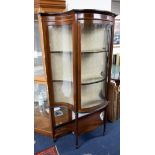 An Edwardian mahogany display cabinet with serpentine shaped glass.