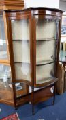 An Edwardian mahogany display cabinet with serpentine shaped glass.