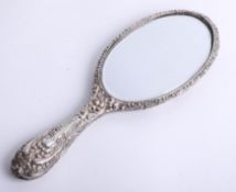 A silver hand mirror with heavy embossed scroll and ribbed decoration, mirror in good condition,