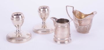 A pair of silver short desk candlesticks, silver cream jug and another, (weight of jug 113g).