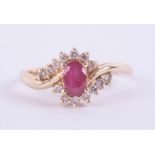 A 14ct modern ruby and diamond oval cluster ring, set in yellow gold, set with 14 round brilliant