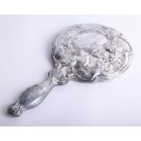 A silver hand mirror with heavy embossed flower and ribbon decoration, mirror slightly misted,