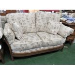 PAIR OF ERCOL MID ELM FRAMED TWO SEATER SOFAS WITH PALE UPHOLSTERED CUSHIONS PATTERNED WITH FLORAL