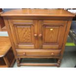 ERCOL MID ELM TWO DOOR CABINET WITH SINGLE DRAWER BENEATH, STANDING ON SHORT TURNED LEGS