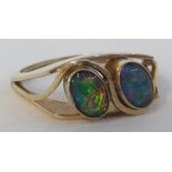 Yellow metal ring set with two opal doublets (each 7mm x 4mm) in cross-over setting, shank stamped