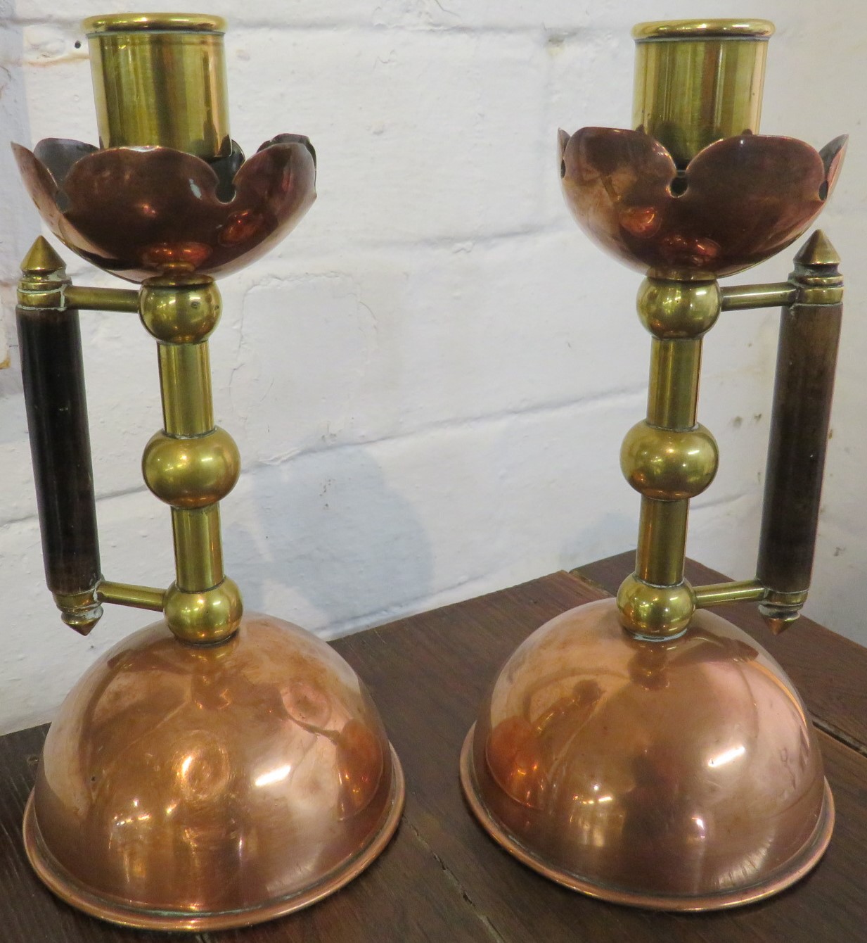 Matched pair of Christopher Dresser designed candlesticks, copper and brass with domed bases and