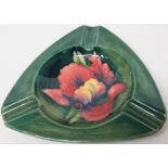 Moorcroft pottery triangular ashtray, green ground decorated with red and yellow hibiscus,