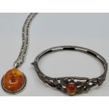 An oval amber pendant in white metal setting stamped SILVER, on hallmarked silver neck chain; and