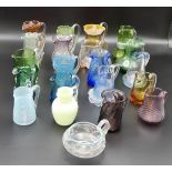 A collection of twenty-one assorted Victorian and later coloured glass jugs, several with applied