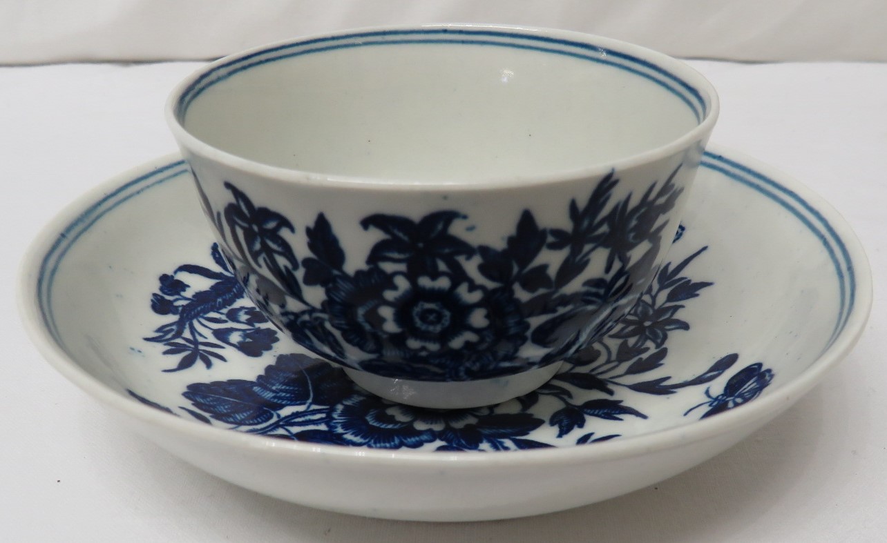 Early Caughley blue and white tea bowl and saucer, patterned with flowers and butterflies, double-