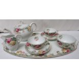A continental white porcelain tea set for two decorated with pink and yellow roses, marked Sevres