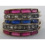 A quintuple dress ring set with a row of thin blue stones, two rows of thin red stones, and two rows