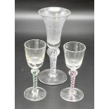 A selection of three wine glasses including a green and cranberry double helix stem and an early