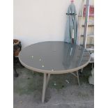 CIRCULAR METAL TABLE WITH GLASS TOP TOGETHER WITH A PARASOL