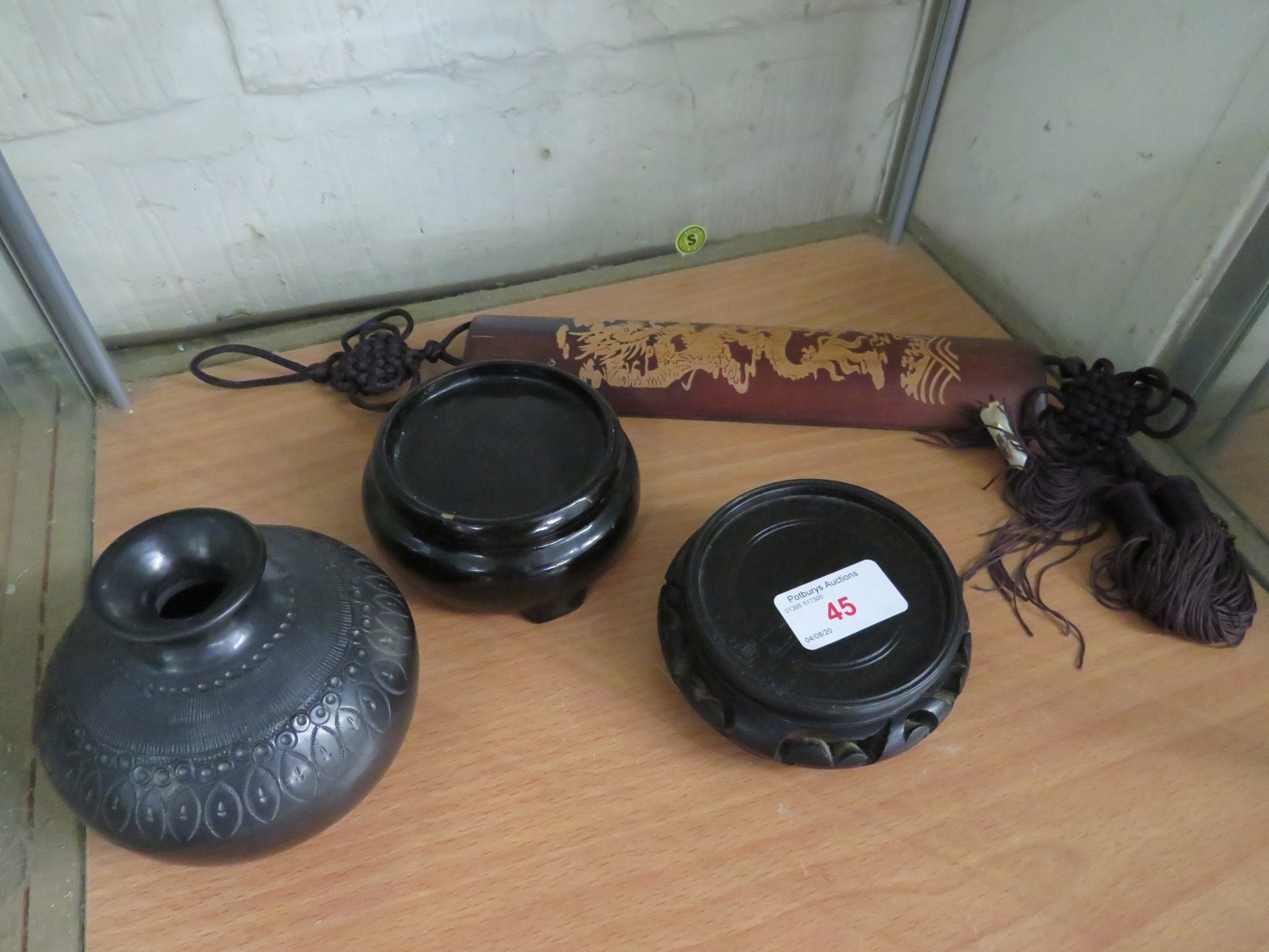 A CARVED BAMBOO WRIST REST WITH TASSLES, A CARVED CERAMIC OVOID VASE IN DARK GREY GLAZE (HEIGHT 8.