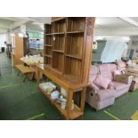 A modern oak bookcase or dresser with nine adjustable shelves to the top under a shaped cushion