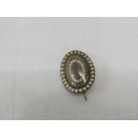 AN OVAL MOURNING BROOCH SET WITH KNOTTED HAIR AND TWO HALOES OF SEED PEARLS (OVERALL 19MM X 15MM),