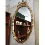OVAL WALL MIRROR IN DECORATIVE GILT FRAME.
