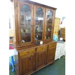 STAINED HONEY PINE GLAZED AND ILLUMINATED DRESSER WITH THREE DRAWERS AND THREE DOORS TO ITS BASE