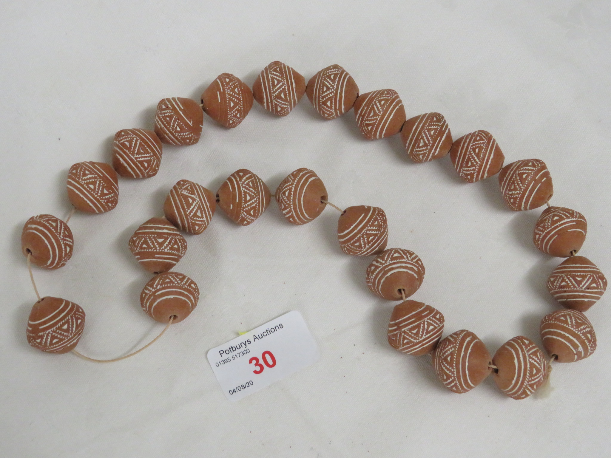 TWENTY-FIVE TERRACOTTA AND HAND DECORATED AFRICAN THREADED BEADS