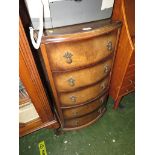 Narrow bow fronted mahogany veneered chest of five drawers with decorative metal handles.