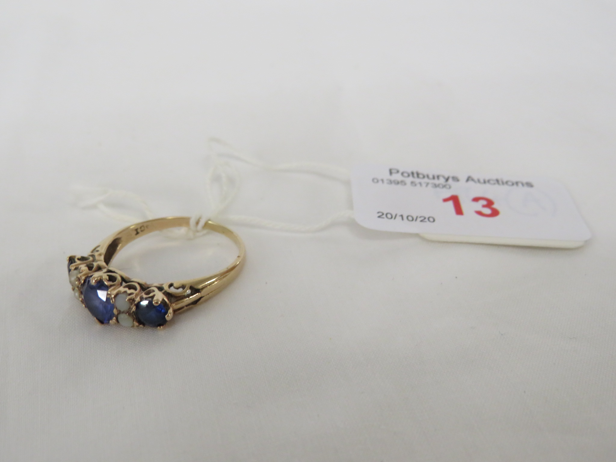 A SAPPHIRE AND PEARL RING WITH SHANK INDISTINCTLY STAMPED 9CT, SET WITH A CENTRAL PALE SAPPHIRE (